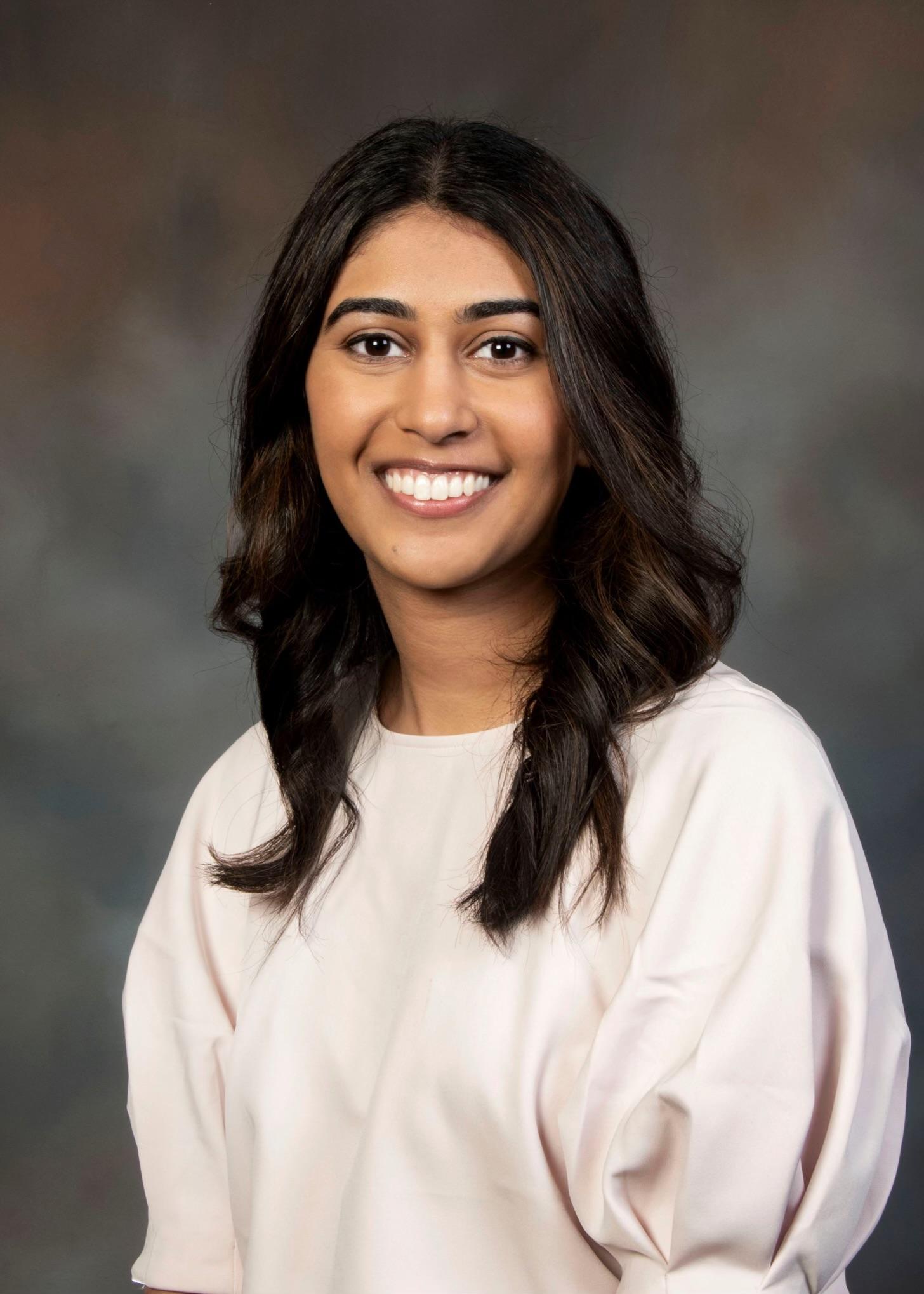 Close-up portrait of Dr. Meera Patel, a dentist, smiling warmly.